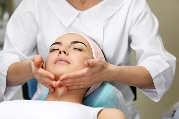 Jonge vrouw met gezicht massage — Stockfoto