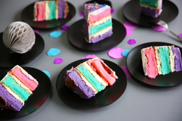 Colorful cake slices on black plates — Stock Photo, Image