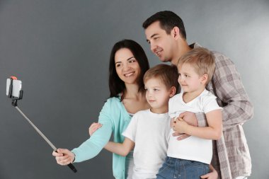 Mutlu aile selfie selfie sopa ile gri arka plan üzerinde yapma