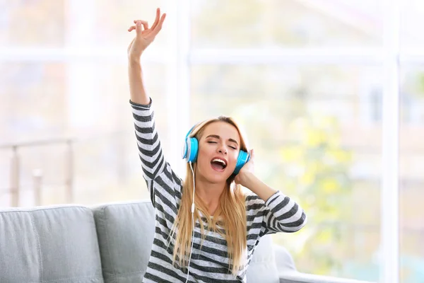 Mulher em um sofá ouvindo música — Fotografia de Stock