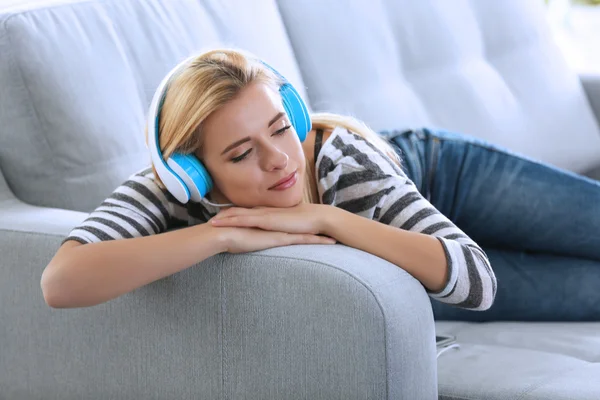 Mujer en un sofá escuchando música — Foto de Stock