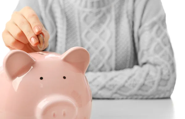 Woman putting coin into a piggy bank — Stock Photo, Image