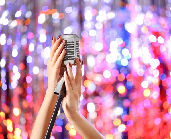 Mãos femininas segurando microfone — Fotografia de Stock