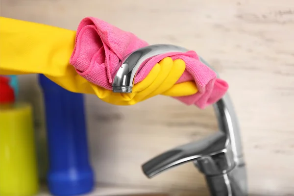 Weibliche Hand mit Lappen, der einen Wasserhahn reinigt — Stockfoto