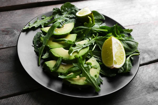 Avocado affettato con calce su placca nera — Foto Stock