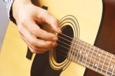Adam akustik gitar çalıyor.