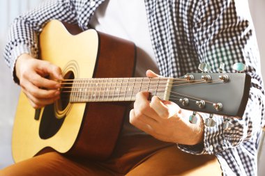 Adam akustik gitar çalıyor.