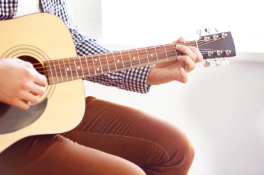 Adam akustik gitar çalıyor.