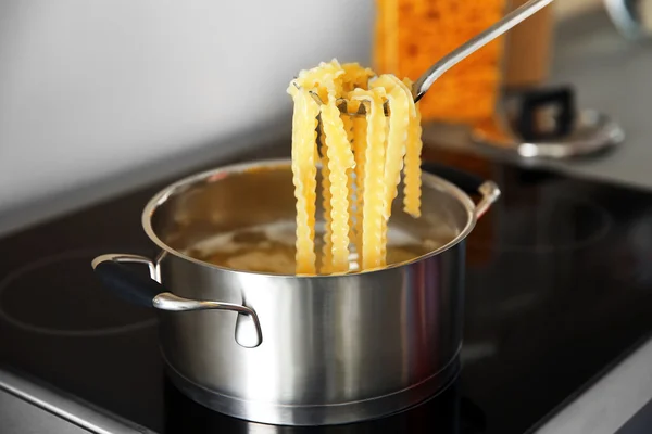 Pasta in spoon over pan on stove — Stock Photo, Image