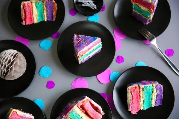 Colorful cake slices on black plates — Stock Photo, Image