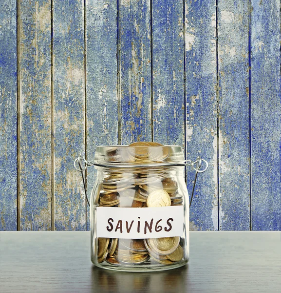 Jar for savings full of coins on wooden background — Stock Photo, Image