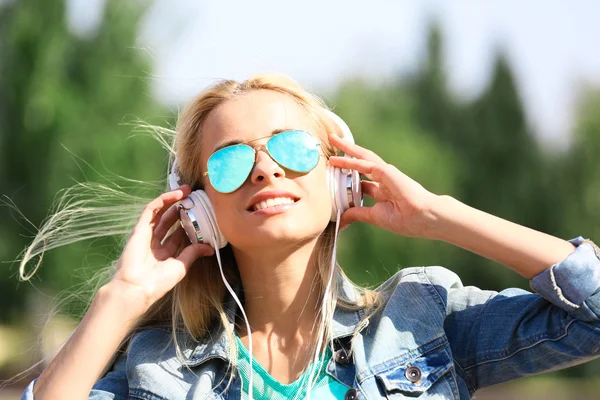 Vrouw die buiten naar muziek luistert — Stockfoto