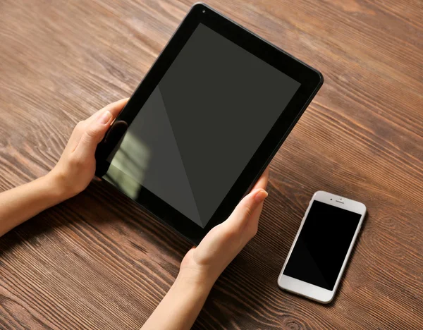 Telefone celular e mãos femininas usando tablet — Fotografia de Stock