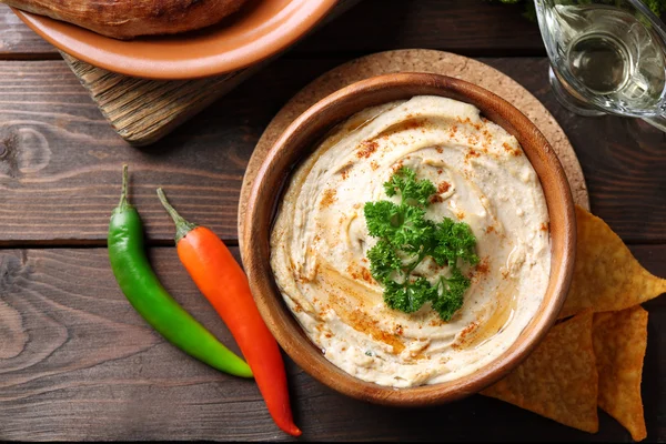 Hölzerne Schüssel mit schmackhaftem Humus — Stockfoto