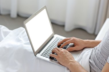 Dizüstü bilgisayar ile yatakta oturan adam