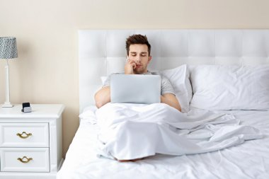 dizüstü bilgisayar ile yatakta yatan adam