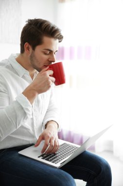 dizüstü tutarak ve kahve içme adam