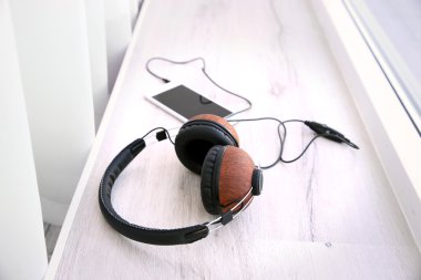 Şık kulaklıklar ve pencere üzerinde cep telefonu