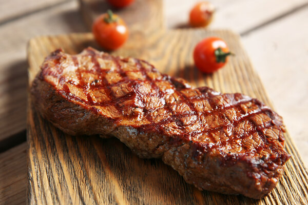 Grilled steak on cutting board with cherry tomatoes, closeup