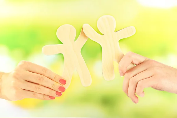 Hands holding a couple of wooden figures — Stock Photo, Image