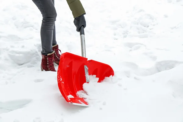 Mujer quitando nieve con pala roja —  Fotos de Stock