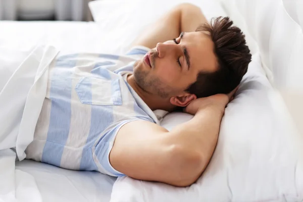 Молодой человек, спящий на кровати — стоковое фото