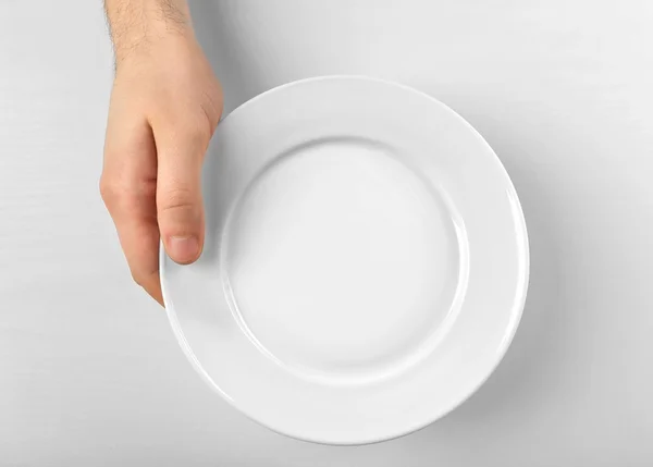 Мужская рука с белой тарелкой — стоковое фото
