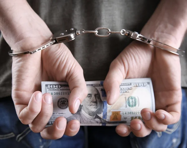 Чоловік в наручниках тримає доларові банкноти — стокове фото