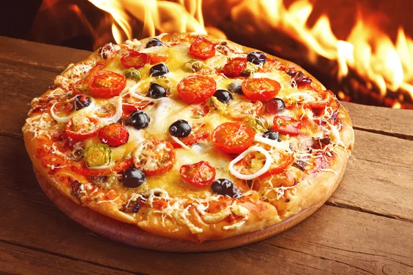 Delicious hot pizza on wooden table — Stock Photo, Image