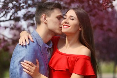 Genç sevgili çift sarılma ve bahar parkta gülümseyen