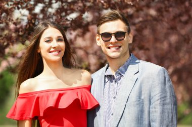 Genç sevgi dolu iki yürüyor ve bahar parkta gülümseyen