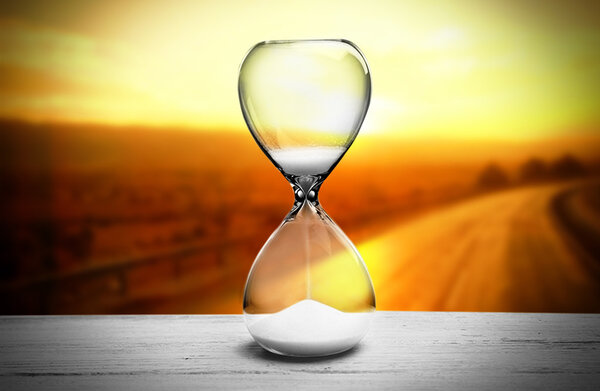 Hourglass on blurred yellow sunset