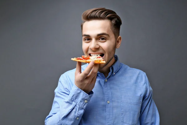 Fiatal jóképű ember eszik pizza — Stock Fotó