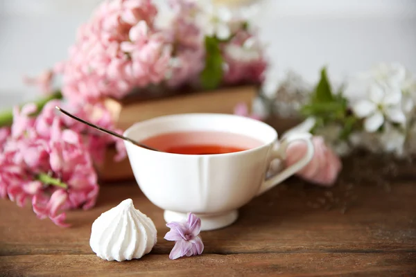 Чашка чая и цветы на деревянном столе — стоковое фото