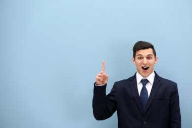 Hafif mavi duvara elbiseli çekici genç adam