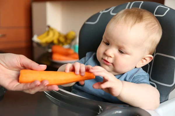Mão feminina dando cenoura ao bebê — Fotografia de Stock