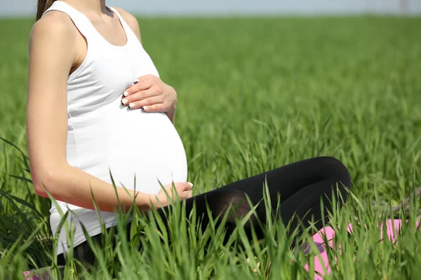 Gravid kvinna avkopplande i fältet — Stockfoto