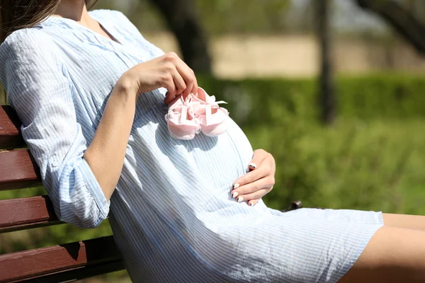 Femme enceinte tenant des bottines de bébé — Photo