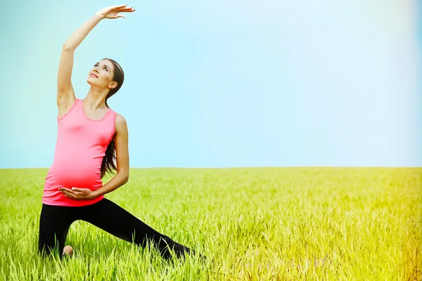 Zwangere vrouw praktizerende yoga vormen — Stockfoto