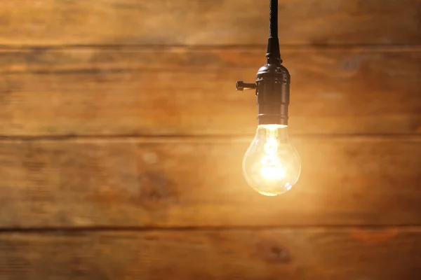 Bombilla brillante sobre textura de madera — Foto de Stock