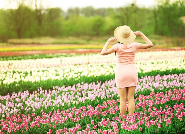 Vrouw op bloeiende gebied van tulpen — Stockfoto