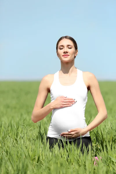 Беременная женщина отдыхает в поле — стоковое фото