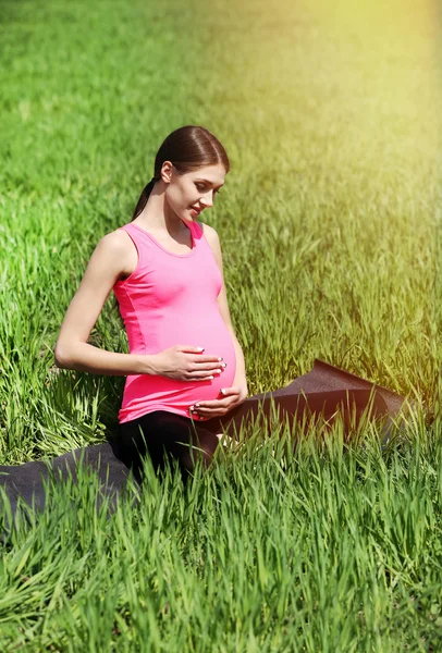 Беременная женщина отдыхает в поле — стоковое фото
