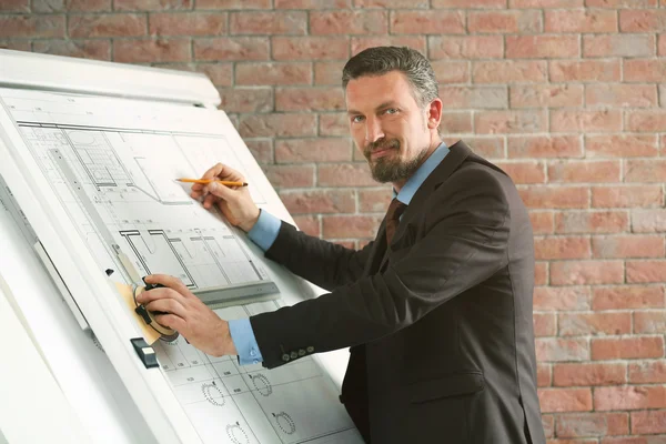 Engineer working with blueprint on panel board indoors