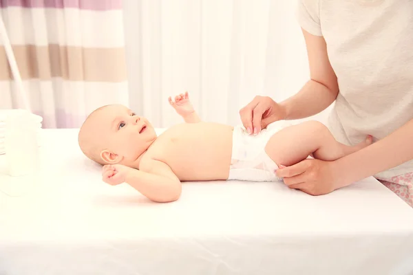 Madre cambiando pañal a pequeño bebé —  Fotos de Stock