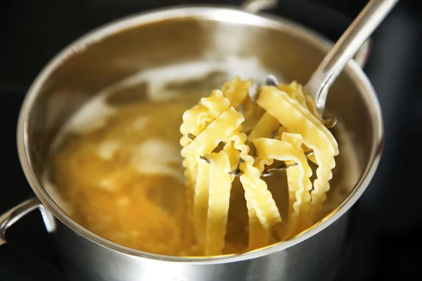 Pasta in cucchiaio sopra padella sui fornelli — Foto Stock