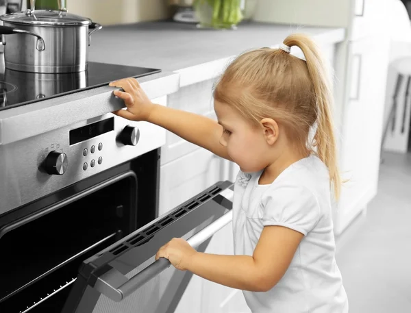 小女孩玩在厨房的烤箱 — 图库照片