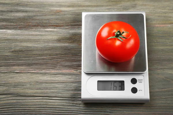 Помидор с цифровыми весами на кухне — стоковое фото