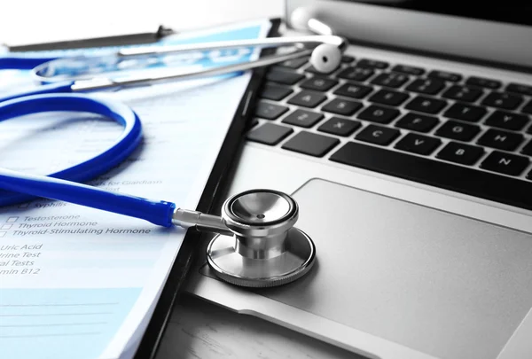 Stetoskop med medicinska formulär och laptop — Stockfoto