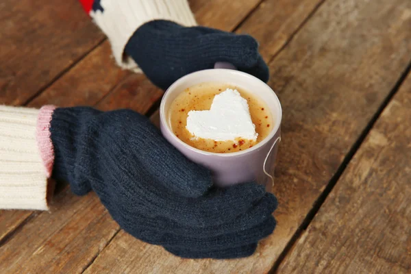 Händer i vantar med en kopp kaffe — Stockfoto